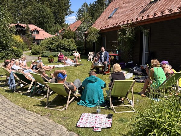 Koncert relaksacyjny w plenerze, uczestnicy na leżakach wśród zieleni